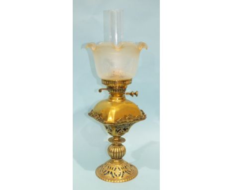 A late-19th/early-20th century oil lamp, the domed rectangular brass reservoir and later etched glass shade, on pierced stand