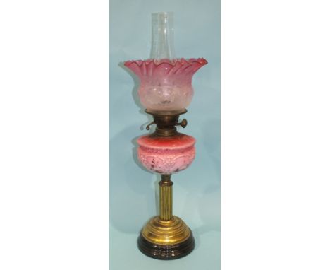 A Victorian oil lamp with etched pink glass shade and moulded pink glass reservoir, on lacquered brass and ceramic stand, 65c