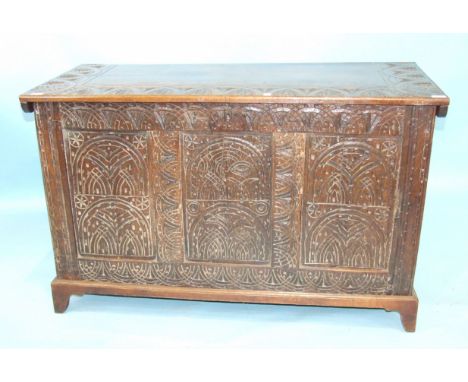 An antique oak coffer, the later top above carved front panels and later bracket feet, 127cm wide, 77cm high.