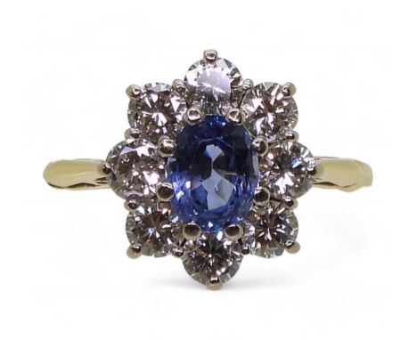 A SAPPHIRE & DIAMOND RING mounted in 18ct gold the classic flower cluster is set with a 6.1mm x 4.7mm x 3.3mm cornflower blue