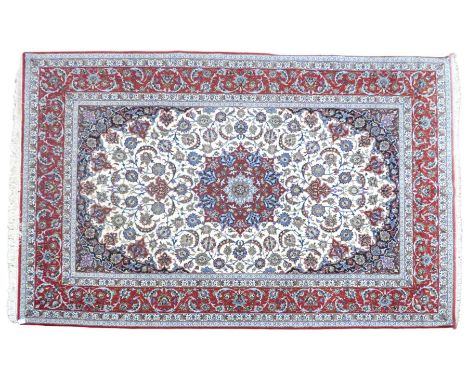 AN IVORY GROUND FULL PILE PERSIAN ISFAHAN CARPET  with red central medallion and dark blue spandrels on floral/foliate patter