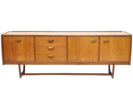 A MID 20TH CENTURY TEAK PORTWOOD SIDEBOARD&nbsp; with three drawers flanked by fall front drinks compartment to left and pair