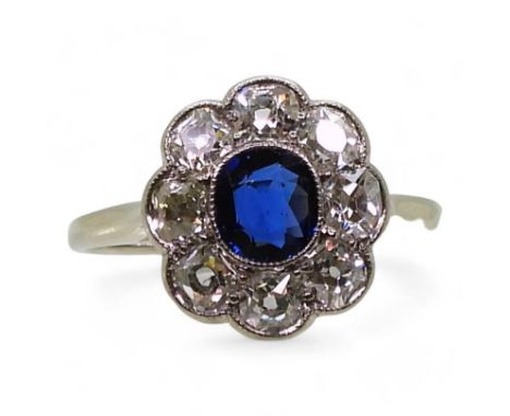 A SAPPHIRE & DIAMOND RING in the classic flower formation, with a handmade white metal galleried mount. set with a central sa