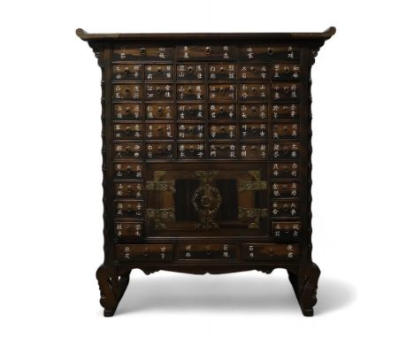 A CHINESE APOTHECARY CABINET With multiple drawers above a pair of doors and on scroll feet,each drawer inset with bone text,
