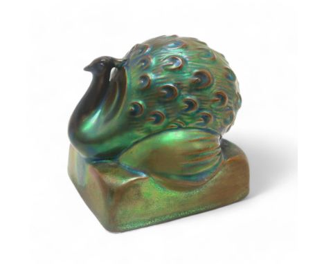 A ZSOLNAY ART DECO EOSIN PEACOCK modelled sitting upon square plinth, impressed marks and number 8135 to base, 9cm high Condi