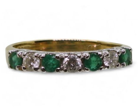 A HALF ETERNITY RING made in yellow and white 18ct gold, and set with four emeralds and three diamonds with a combined carat 