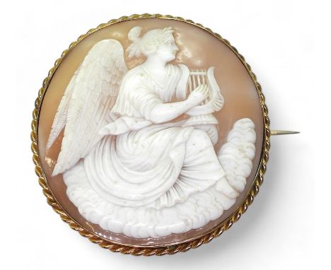 AN ANGEL CAMEO a finely carved shell cameo of an Angel playing a harp, in a gold plated brooch mount. Diameter 6.5cm, weight 