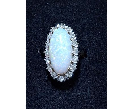 Hallmarked 18ct yellow gold ring with a large central oval cut opal ( approx 15mm long ) surrounded by 16 round cut diamonds 