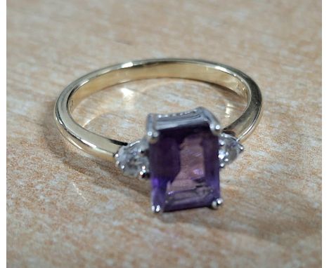 9ct yellow gold ring with a large emerald cut Amethyst, flanked to either side by a small round cut diamond, 2.8 grams gross 