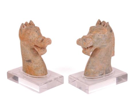 A similar near pair of Chinese weathered green carved Jade figures of horse heads, possibly Han Dynasty, each with curved lip