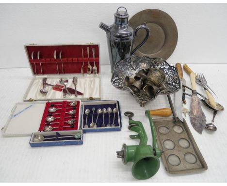 A collection of metalware comprising of a mincer, silver plated bowl, cutlery, egg cups, pewter plate, bell, spoon sets in bo