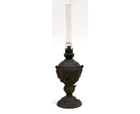 A gilded spelter oil lamp decorated in relief with a colonial African battle scene, 31cms (12.75ins) high.