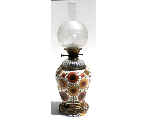 A Victorian oil lamp with ceramic body decorated with flowers, cut glass reservoir and gilt metal mounts, stamped J Hinks & S