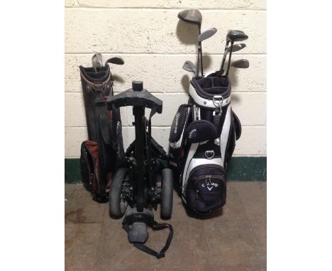 A collection of golf clubs, two golf bags and a caddy. 