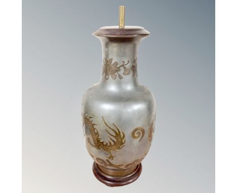 An oriental metal table lamp decorated with dragons and flowers. 