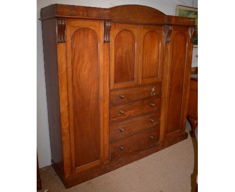 A Victorian mahogany breakfront wardrobe, with arched cornice, above two central arched cupboard doors, flanked by cupboard d