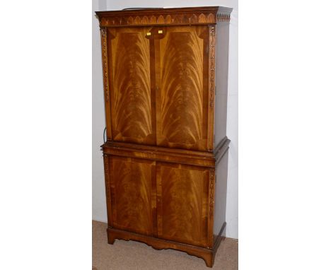 A reproduction flamed mahogany cocktail cabinet, with arched moulded frieze, fitted glazed interior, cupboards below, on brac