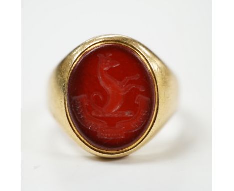 An 18ct and oval intaglio carnelian set signet ring, carved with family crest and motto, size K, gross weight 6.9 grams.