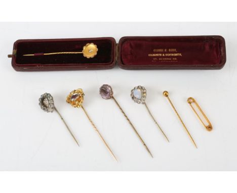 Six stick pins and a bar brooch, including one in the design of a flower head set with a rose cut diamond to the centre, in s