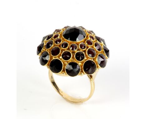 Dome ring set with garnets, central faceted round cut garnet with a surround of three graduated rows, in stamped 14 ct yellow