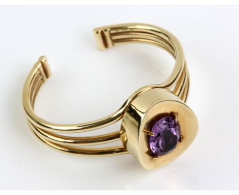 A bespoke amethyst torque bangle, with a central oval cut amethyst weighing an estimated 8.00 carats, claw set in a wide conc