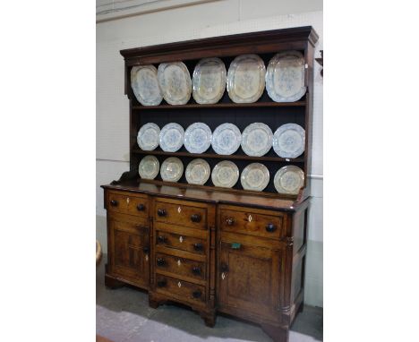 An Antique Oak Anglesey Dresser Having A Reduced Two Shelf Rack, The Break-Front Base Having Two Side Cupboards Each With Dra