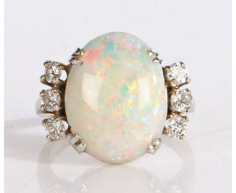 Opal and diamond ring, the central oval opal flanked by three diamonds to each shoulder, on a white metal band, ring size P, 