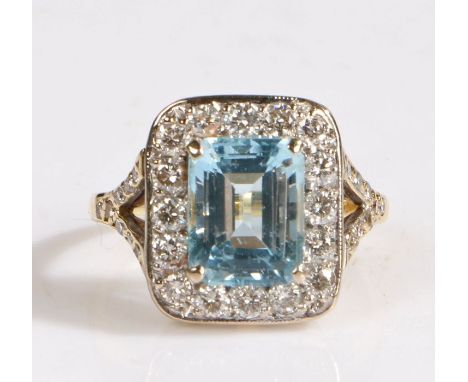 A 18 carat gold diamond and aquamarine ring, the head set with a baguette cut aquamarine stone surrounded by round cut diamon