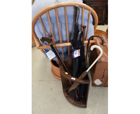 An Edwardian oak framed stick stand with a selection of walking sticks and umbrellas