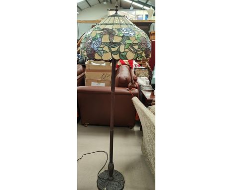 An Art Nouveau style bronzed metal standard lamp with a Tiffany style shade. 