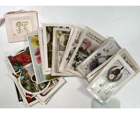 A selection of vintage postcards, many embossed with flowers