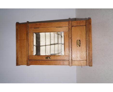 A 19th Century pine hanging cupboard, probably Welsh, with a bevelled mirror door enclosing a shelved interior, a drawer belo