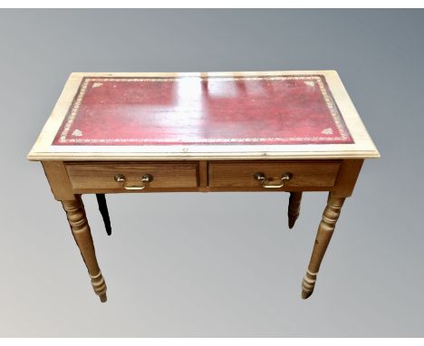 A pine two drawer writing table with red tooled leather inset panel on raised legs 