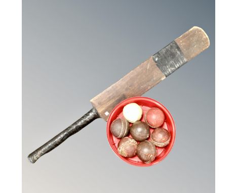 A vintage wooden cricket bat together with seven cricket balls 