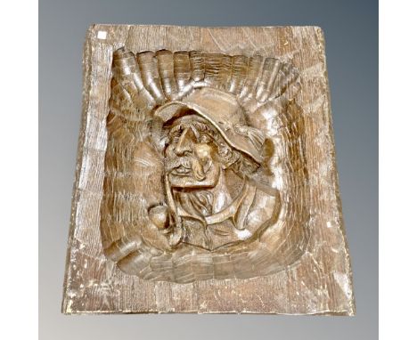 A carved wooden panel depicting a man smoking a pipe 