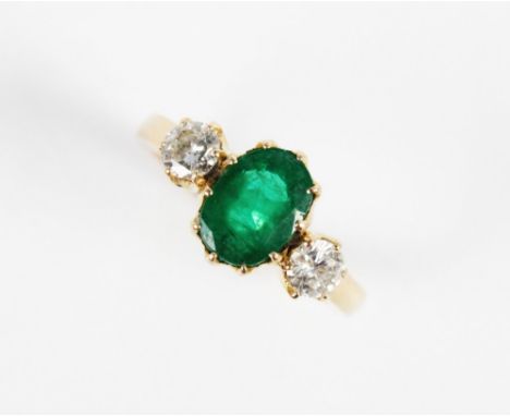 An emerald and diamond 3-stone ring, the central oval mixed cut emerald (measuring 8.5mm x 6.5mm x 5mm), with a round brillia