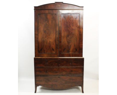 An early 19th century mahogany linen press, the architectural pediment above a pair of flame mahogany doors, opening to five 
