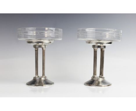 A pair of Art Deco tazzas, the shallow glass dishes with etched geometric motifs, raised on white metal stands comprising fou