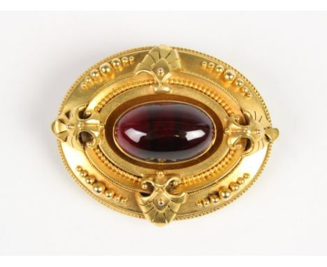 A Victorian Etruscan style memorial brooch, comprising a central garnet cabochon measuring 19mm x 12mm, set to an oval yellow