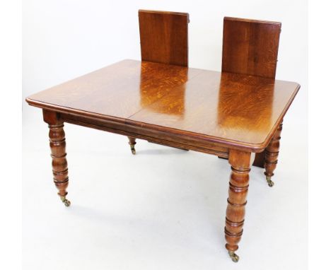 An early 20th century golden oak extending dining table, the rectangular top with moulded and rounded corners, raised upon ri