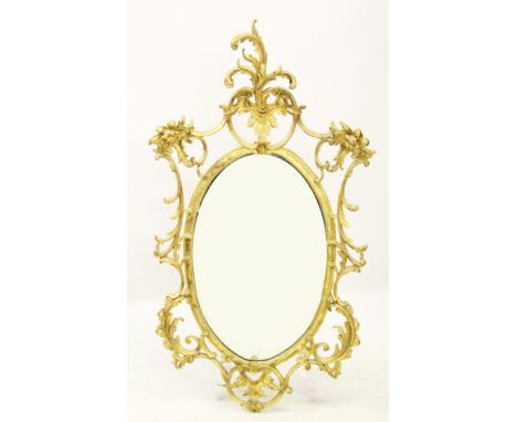 A late 19th/early 20th century French Rococo style gilt wood wall mirror, the oval mirror plate enclosed by a C-scroll open w