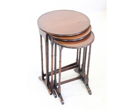 An Edwardian mahogany nest of tea tables, each with a circular tray top raised upon slender ring turned legs and down swept s