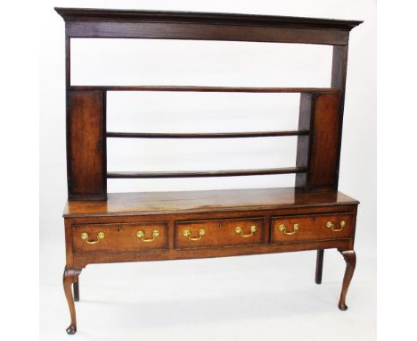 A George III oak and mahogany cross banded Welsh dresser, the open plate rack with a cavetto cornice over three open shelves,