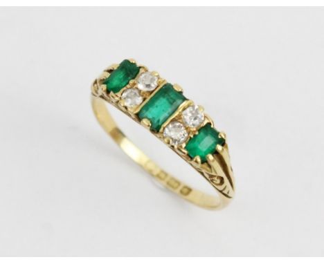 A Victorian/Edwardian emerald and diamond 18ct gold ring, the central rectangular step cut emerald (measuring 5mm x 2.5mm), w