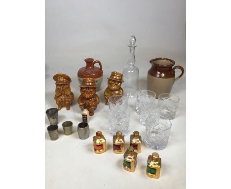 A decanter together with tumblers, drinks measures, miniatures, Torquay Pottery character jugs and other items