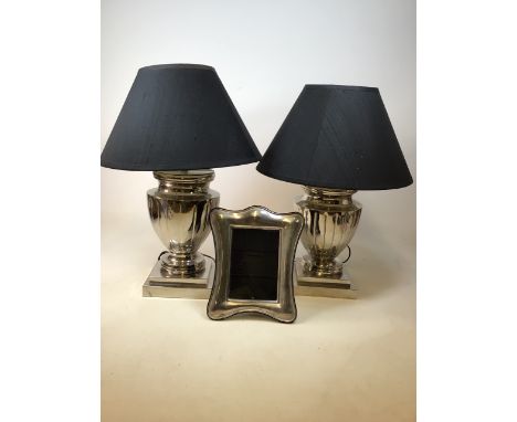 Two contemporary lamps with mirrored metal bases and black shades together with a silver coloured frame. Lamp bases 44cm high