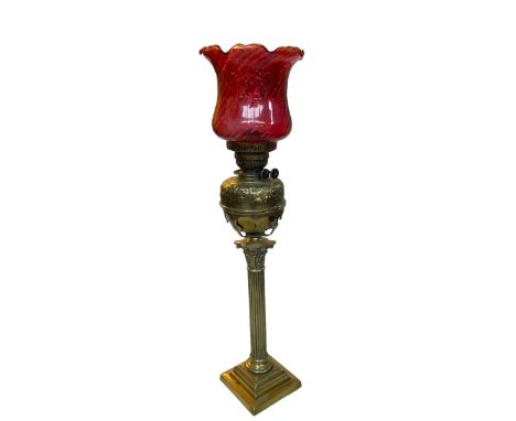 Vintage ornate brass columned oil lamp with red glass shade, 85cm.