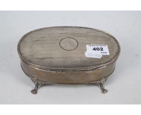 An Edwardian silver dressing table box of oval section raised on four paw supports, Sheffield assay 1908, approximately 334 g