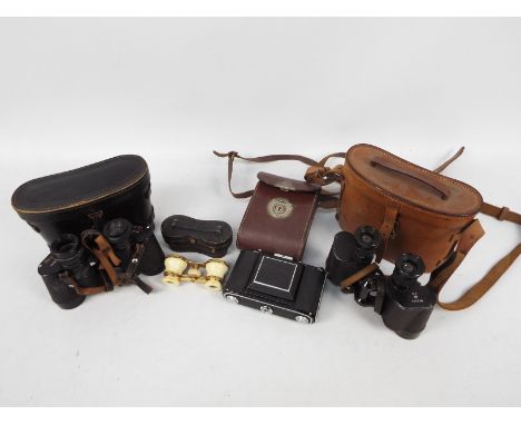 Two cased pairs of binoculars, a pair of gilt brass and ivorine opera glasses and a Zeiss Ikon camera (cased).