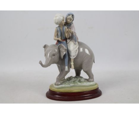 A Lladro figure group # 5352 Hindu Children, approximately 23 cm (h), with wooden display base.